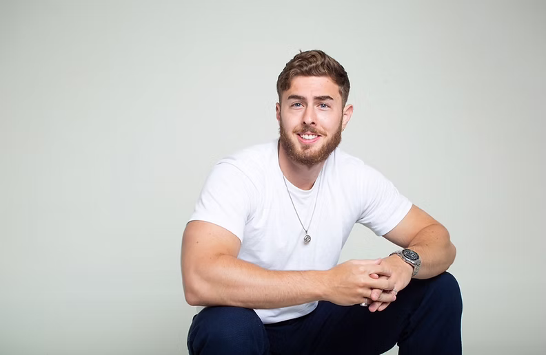 Calum, founder and personal trainer at Unity, Strength & Wellness in Hastings, seated in a white T-shirt